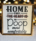 Funny wood sign reading Home is where you poop most comfortably with rustic frame