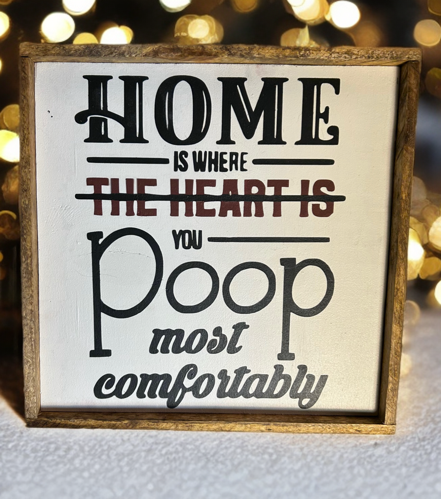 Funny wood sign reading Home is where you poop most comfortably with rustic frame