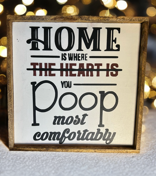 Funny wood sign reading Home is where you poop most comfortably with rustic frame