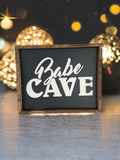 Funny dark wood sign reading Babe Cave in script and block lettering with rustic wood frame